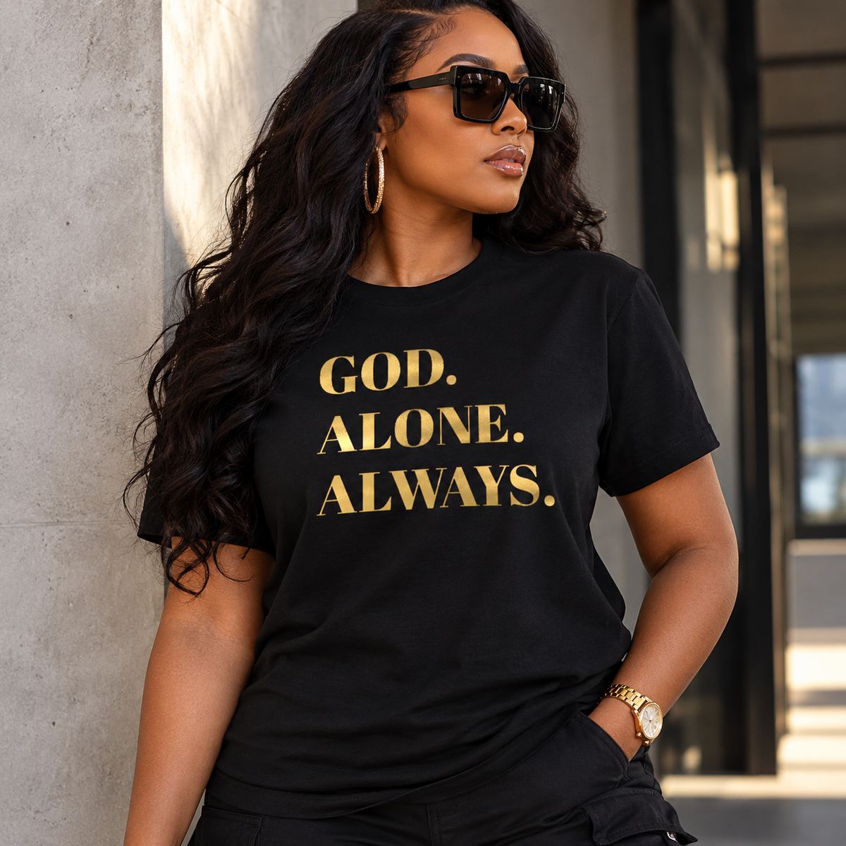 Model wearing a black God. Alone. Always. tee with metallic gold lettering.